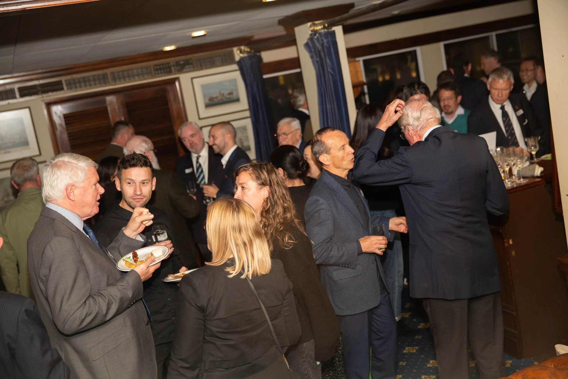 Members in conversation over drinks at a Company reception.