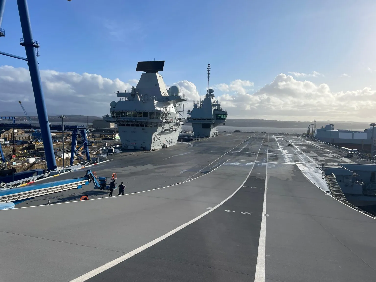 The flight deck of HMS Queen Elizabeth (R08) at Rosyth, with a destroyer alongside